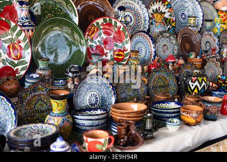 Vivace assortimento di piatti in ceramica smaltata sul tavolo da lavoro, bazar Siab all'aperto. File di piatti decorativi tradizionali con fiori motivi paisley, han Foto Stock