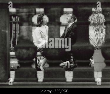 Fotografia storica intitolata "coppia seduta su una panchina a New York City", che mostra un uomo e una donna che conversano faccia a faccia su una panchina del parco, vista attraverso una ringhiera di pietra. Fotografia di Angelo Rizzuto, settembre 1956 Foto Stock