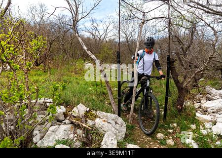 Una ciclista in viaggio in bicicletta nel tardo primavera lungo i sentieri delle colline carsiche di Slavnik, godendosi le viste panoramiche di Primorska, Slovenia. Foto Stock
