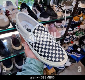 Mano che tiene una scarpa slip-on classica a scacchi in un ambiente di vendita al dettaglio Foto Stock
