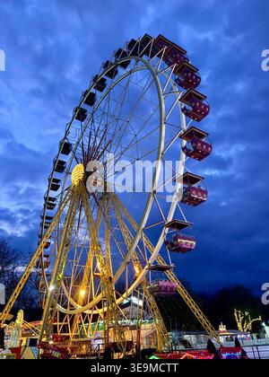 Ruota panoramica illuminata di notte sotto il suggestivo cielo blu Foto Stock