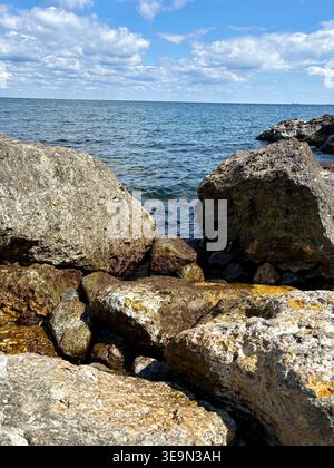 Grandi rocce costiere contro il profondo mare blu e il cielo nuvoloso Foto Stock
