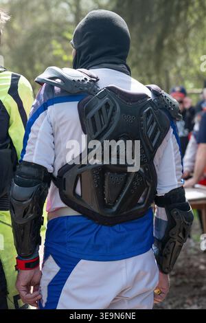 Primo piano di un motociclista da dietro che indossa un'armatura professionale, una protezione per il torace e dei gomiti durante le competizioni enduro. Foto Stock