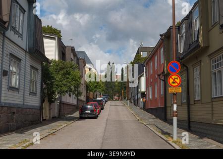 HELSINKI, FINLANDIA - 11 AGOSTO 2025: Stretta strada residenziale fiancheggiata da colorati edifici in legno e mattoni in una giornata estiva. Foto Stock