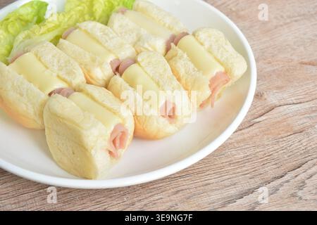 arrotolare il pane ripieno di prosciutto di maiale e formaggio con lattuga fresca sul piatto Foto Stock