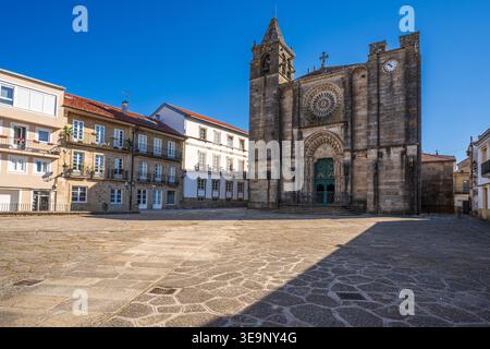 Una vista soleggiata sulla facciata gotica della Chiesa di San Martino in Noia. La foto cattura la grande rosetta, il portale scolpito e la campana incompiuta Foto Stock