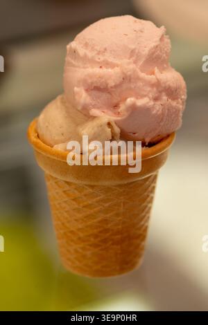 Gelato al cono di cialde con due gusti servito da vicino su sfondo sfocato. Foto Stock