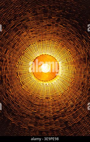 Una vista ipnotizzante degli interni a cupola che mostrano un dettagliato motivo di mattoni illuminati da una luce centrale. Foto Stock