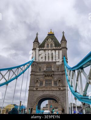 Un grande e vecchio edificio con una cupola dorata si trova di fronte ad un ponte. Il cielo è nuvoloso e l'edificio è circondato da un ponte blu Foto Stock
