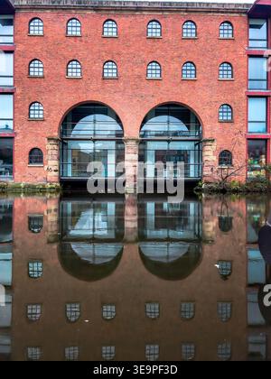 Un edificio in mattoni con finestre ad arco e una grande finestra sul fronte. L'edificio è circondato dall'acqua Foto Stock