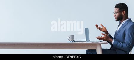 Riunione d'affari che si svolge con un uomo che parla ad una scrivania in un ambiente ufficio Foto Stock