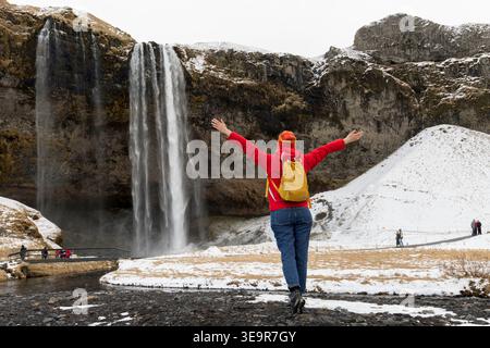 Donna traveler al magico cascata Seljalandsfoss in Islanda si trova vicino alla tangenziale sud di Islanda. Maestoso e pittoresco, è uno dei più pho Foto Stock