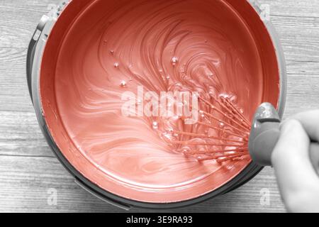 Persona che mescola la vernice di rame in un contenitore di plastica con una frusta di metallo. Decorazione fai da te concetto di miglioramento della casa. Foto Stock
