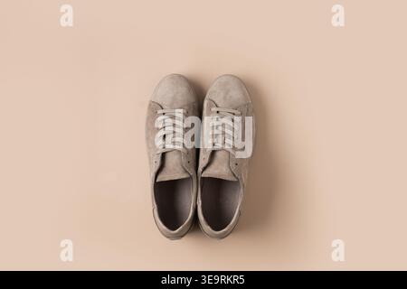 Un paio di sneaker beige scamosciate su sfondo beige neutro, una foto di prodotto alla moda moderna, uno stile minimal. Copia spazio Foto Stock