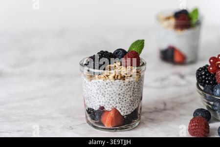 Vista frontale del pudding di chia parfait con frutti di bosco e menta su sfondo chiaro con luce naturale soffusa Foto Stock