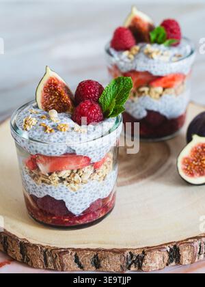 Vista ravvicinata del dolce a strati di chia con fichi frutti di bosco e muesli su tavola rustica di legno Foto Stock