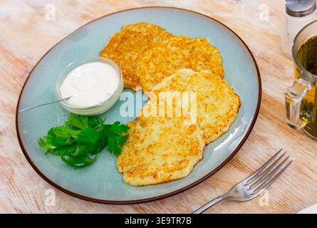 I pancake fritti sono disposti in modo ordinato sul piatto e decorati con foglie di prezzemolo. Foto Stock