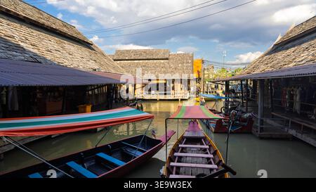 PATTAYA, THAILANDIA - 19 DICEMBRE 2023: Mercato galleggiante tradizionale con edifici in legno e barche a coda lunga su un canale Foto Stock