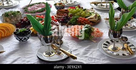 Un tavolo fisso con un vassoio di frutta e insalate e un caminetto bianco sullo sfondo Foto Stock