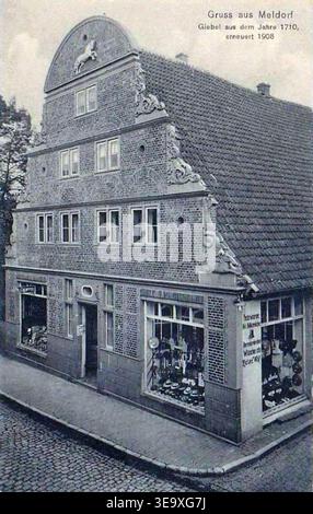 Meldorf è una città dello Schleswig-Holstein, in Germania. La cartolina del 1909 mostra un edificio commerciale per pellicce, cappelli e abbigliamento maschile con un timpano originariamente del 1710, rinnovato nel 1908. L'immagine d'archivio documenta l'architettura commerciale tedesca dell'inizio del XX secolo e la cultura del commercio al dettaglio. Foto Stock