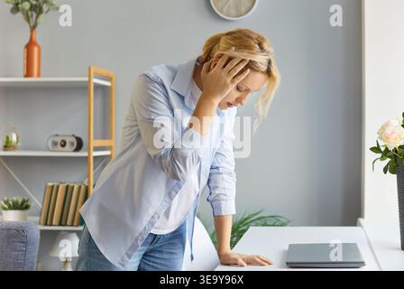 Donna stressata e sovraccarica che soffre di terribile mal di testa o vertigini Foto Stock