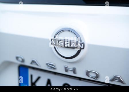 Kiev, Ucraina - 14 luglio 2025: Primo piano di un badge Nissan Qashqai su vernice bianca, che mostra il logo e il dettaglio parziale della targa. Foto Stock