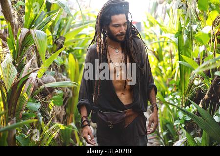 ragazzo alla moda con dreadlocks in palme tropicali sorridenti Foto Stock
