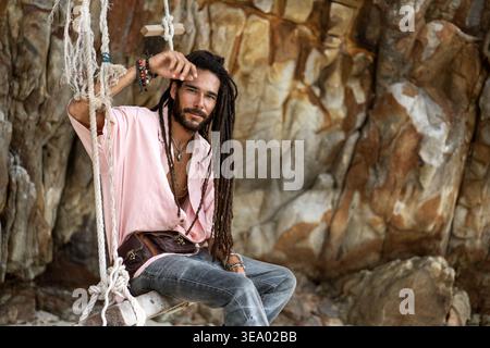 ragazzo europeo con dreadlocks, aspetto asiatico seduto su un swin Foto Stock