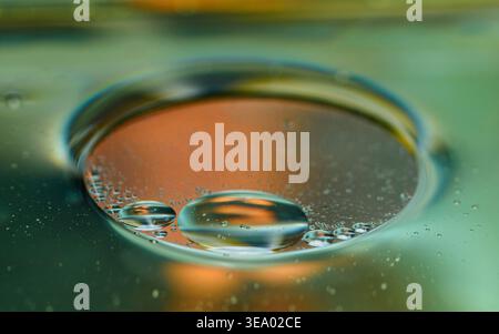 Gocce d'olio sull'acqua che creano forme e texture iridescenti e astratte con sfumature di colore vivaci e motivi fluidi e organici. Fotografia, niente generi Foto Stock