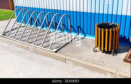 Parcheggio per biciclette vuoto e cestino della spazzatura in città durante il giorno estivo Foto Stock