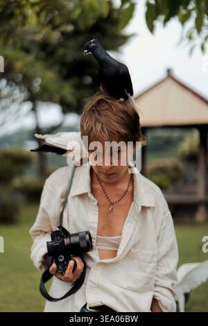Giovane donna con piccione in testa che tiene la macchina fotografica al monastero di Bali Foto Stock