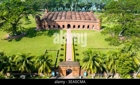 Vista aerea della Moschea Sixty Dome, un punto di riferimento storico con la sua facciata in terracotta e le cupole multiple, che si erge maestosamente in mezzo alla terra verdeggiante Foto Stock