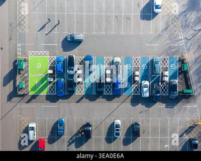 Vista aerea del parcheggio con colorate baie di ricarica elettriche che proiettano lunghe ombre sull'asfalto, Exeter, Inghilterra, Regno Unito. Foto Stock