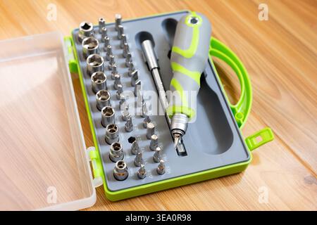 Primo piano. Cacciavite con punte intercambiabili. Un set di punte in acciaio per cacciavite con manico in plastica grigio-verde. Concetto: Miglioramento della casa fai da te Foto Stock