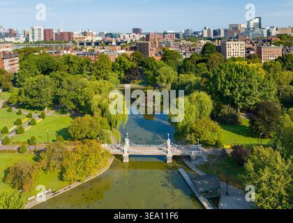 Vista aerea del giardino pubblico con il Ponte della Laguna sul laghetto con persone che camminano lungo sentieri circondati da alberi e lo skyline della città Foto Stock