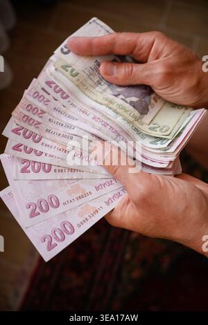 Mani che detengono una pila di banconote in lira turca, concetto finanziario ed economico, pagamento in contanti e cambio valuta in Turchia, inflazione, banche, risparmi e valore valutario, una pila di duecento lire banconote Foto Stock