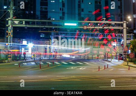 Attraversamento ferroviario a Seoul, Corea del Sud, di notte. La scena include segnali illuminati, barriere e segnaletica orizzontale. Foto Stock