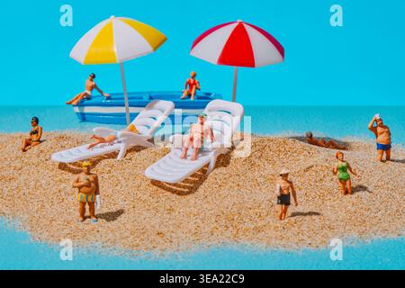 un'ampia vista mostra più persone in miniatura sparsi su una spiaggia sabbiosa con due lettini bianchi sotto ombrelloni a strisce, mentre una piccola barca con s Foto Stock
