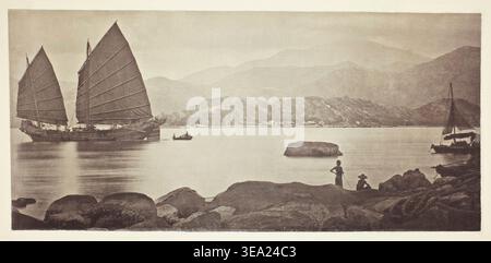 A Canton Trading Junk di John Thomson, c. 1868, che mostra le tradizionali navi a vela cinesi ancorate in un porto costiero montuoso con figure locali che osservano dalle coste rocciose Foto Stock