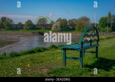Una panchina che si affaccia sul fiume Mersey con il Silver Jubilee Bridge sullo sfondo lunedì 20 aprile 2026. Foto di James Giblin (Alamy sto Foto Stock
