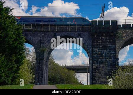 Vista dello storico ponte ferroviario che attraversa il fiume Mersey tra Runcorn e Widnes mentre un treno Avanti West Coast passa lunedì 20 aprile Foto Stock