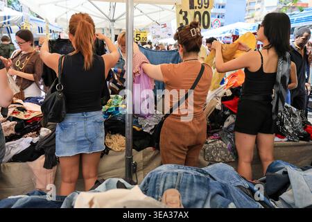 Roma, Italia - 19 aprile 2026: Gli amanti dello shopping sono visti curiosare tra le pile di vari capi d'abbigliamento in una stalla all'aperto a porta Portese. La scena capt Foto Stock