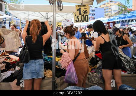 Roma, Italia - 19 aprile 2026: Gli amanti dello shopping sono visti curiosare tra le pile di vari capi d'abbigliamento in una stalla all'aperto a porta Portese. La scena capt Foto Stock