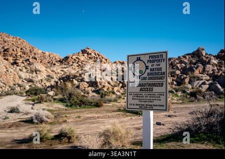 Proprietà privata e cartello con limitazioni di accesso nel paesaggio desertico del Joshua Tree National Park, California, con terreno roccioso e piste sterrate. Foto Stock