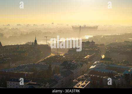 Vista aerea dei tetti della città vecchia di Varsavia e dello Stadio Nazionale avvolto dalla nebbia mattutina durante l'alba dorata di Varsavia, Voivodato della Masovia, Polonia Foto Stock