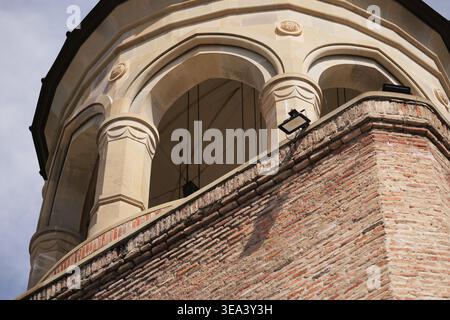 Vista ad angolo basso di un campanile in mattoni e pietra con eleganti archi e dettagli architettonici Foto Stock