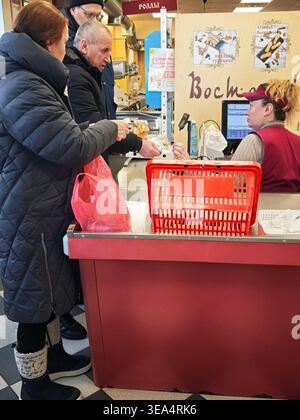 Kirov, Russia - 8 febbraio 2026: I clienti effettuano acquisti al banco cassa mentre interagiscono con il cassiere in un supermercato affollato. Foto Stock