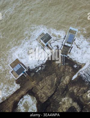 Vista aerea delle capanne di pesca di les Carrelets lungo la costa con onde e rocce, Saint-Palais-sur-Mer, Charente-Maritime, Francia. Foto Stock