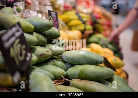 Vari tipi di frutta esotica tropicale al supermercato in Tailandia, il cliente sceglie mango. Foto Stock
