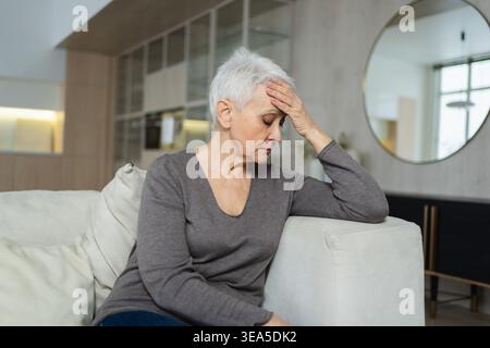Triste stanco malato solo deluso anziana donna seduta a casa da solo. Nonna matura infelice che sperimenta dolore relativa morte cattiva notizia. Stressato anziana che soffre di solitudine Foto Stock